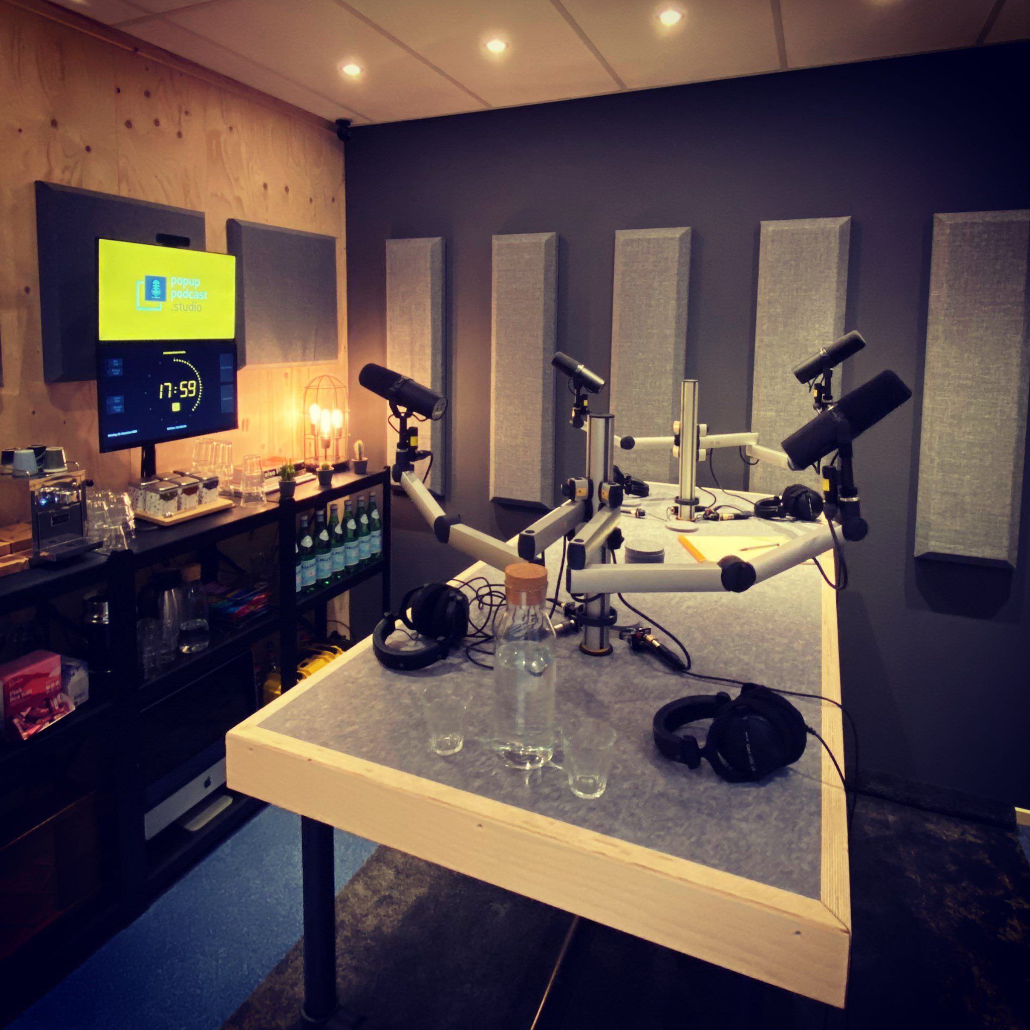 Podcast table with four microphones; OnAirScreen clock and station logo on the wall monitor